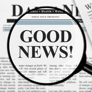 newspaper text with magnifying glass focus on good news