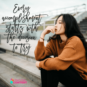 young woman sitting in bleachers in contemplative pose with the quote, "Every accomplishment starts with the decision to try."