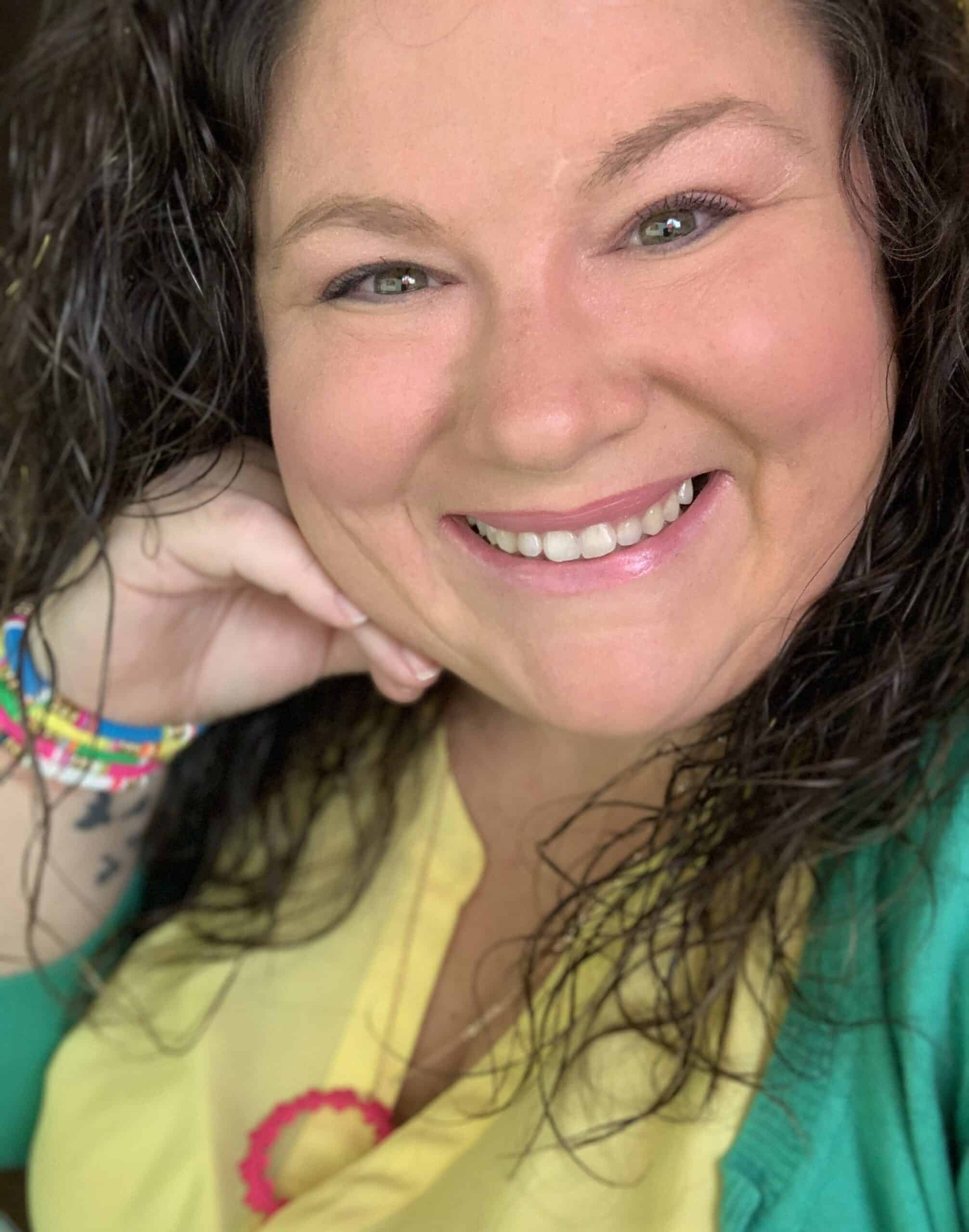 A smiling woman with curly hair and a green shirt.